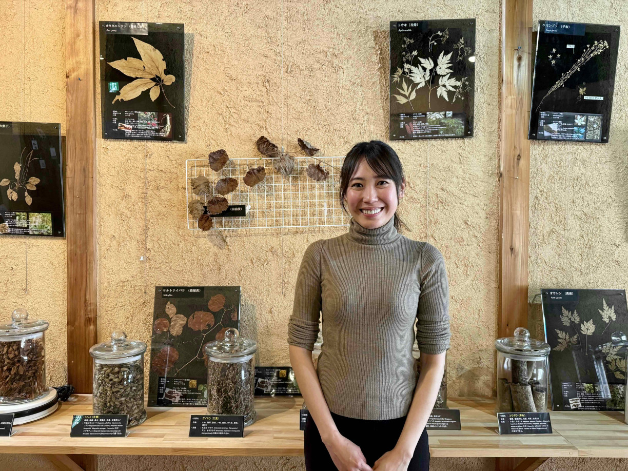 Ms. Menju in front of local Hida herbs and plants